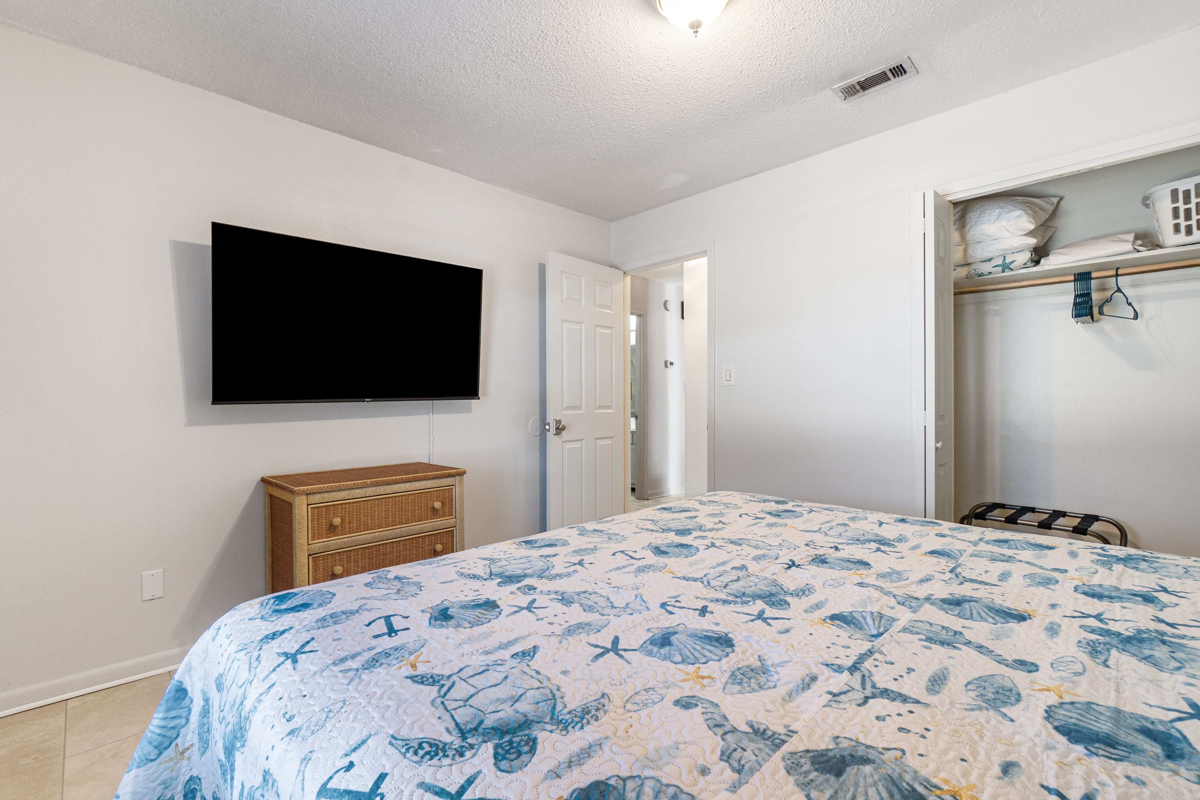 Une chambre à coucher comprenant un lit, une télévision, une armoire et une porte donnant sur une autre pièce.