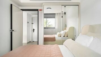 A modern hotel room with a bed, a bedside table, a mirror, and a window.