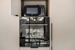 A compact kitchenette with a microwave and a small window overlooking an outdoor seating area. - Eilat Bay Retreat • Sea Views by SeaNRent (Eilat)