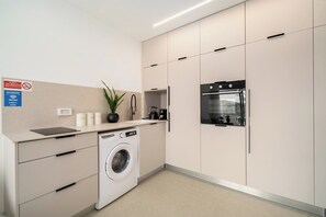 Una cocina moderna con lavadora integrada, una estación de café y un refrigerador.