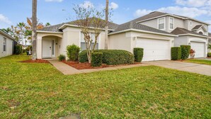 A single-story house with a garage, a front lawn, and a palm tree. - 4BR Lake Berkley Home, Pool & Game Room (Kissimmee)