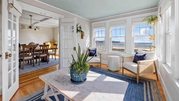 A bright, airy room with a view of the sea, featuring a dining area, a seating area with a view, and a large plant centerpiece. - The Iconic Anchor Haven at Kennebunk Beach (Kennebunk)