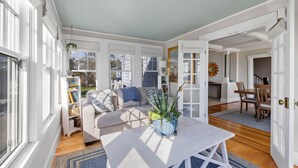 A spacious living room with a white sofa, a coffee table, and a dining area with wooden chairs. - The Iconic Anchor Haven at Kennebunk Beach (Kennebunk)