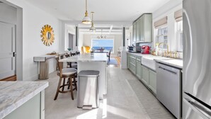 A modern kitchen with a central island, stainless steel appliances, and a view to the outside. - The Iconic Anchor Haven at Kennebunk Beach (Kennebunk)