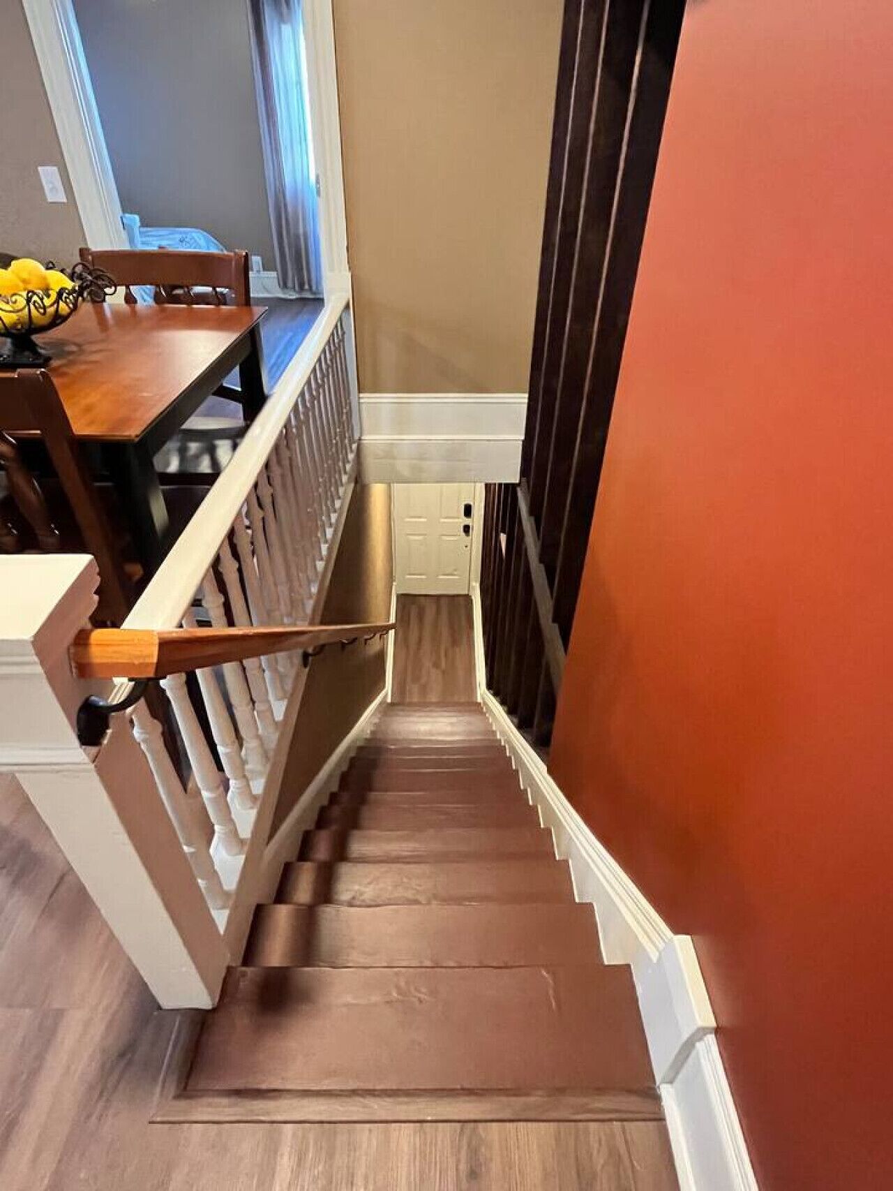 Un escalier avec des marches en bois et des rampes blanches menant à un palier.