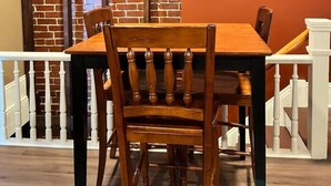 A dining area with a brick wall, a flat-screen TV mounted above a wooden table and chairs. - Extended Loft. Near AT, C&O, Harper`s Ferry (Brunswick)