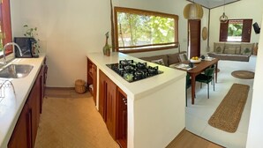 Une cuisine compacte équipée d’une cuisinière à gaz, d’un évier et d’un coin repas avec une table et des chaises.