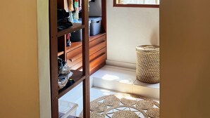 Un dressing ouvert avec des étagères en bois, un panier en osier et un tapis à motifs.