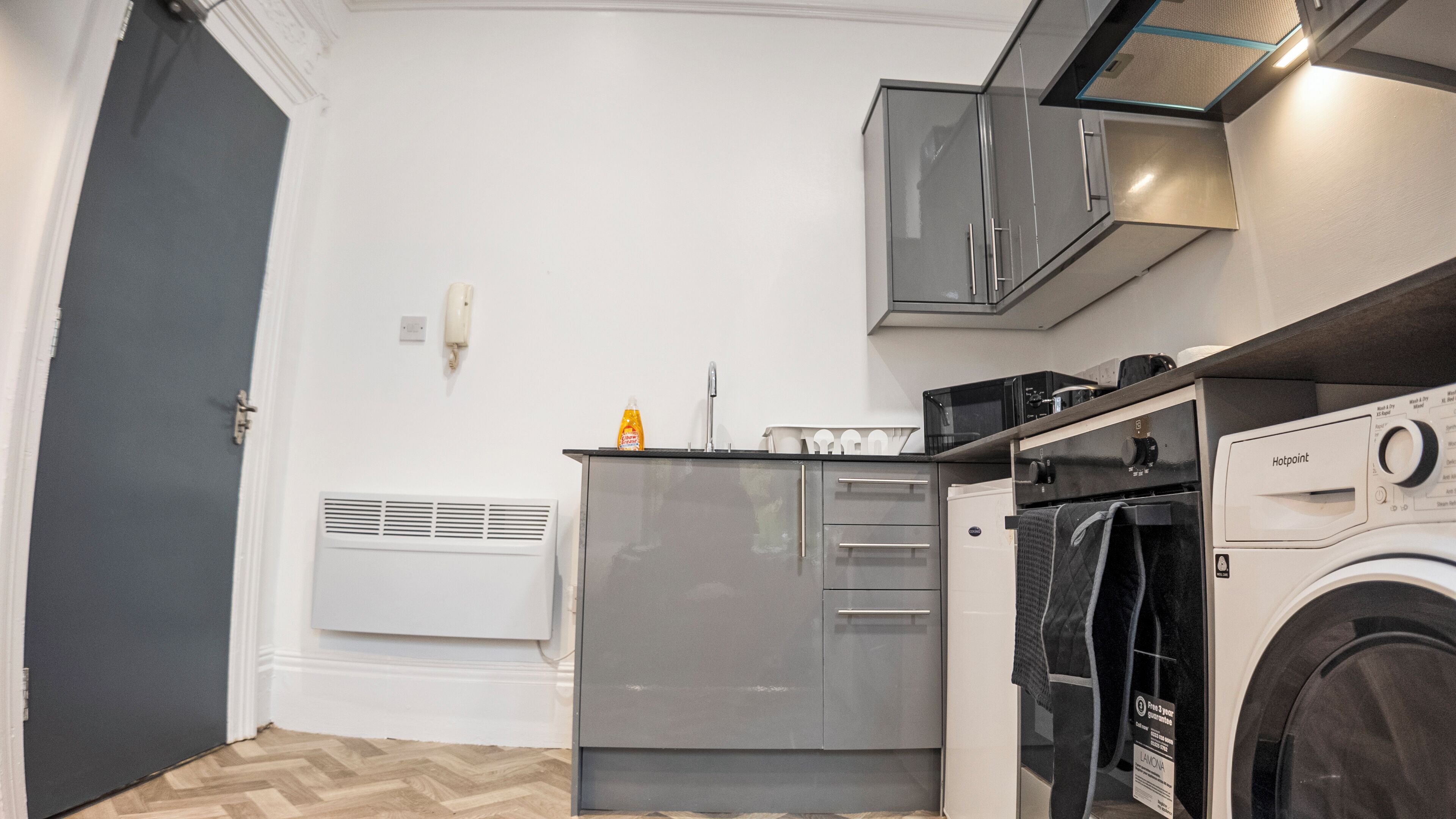 A compact kitchen with a built-in dishwasher, a washing machine, and a microwave.