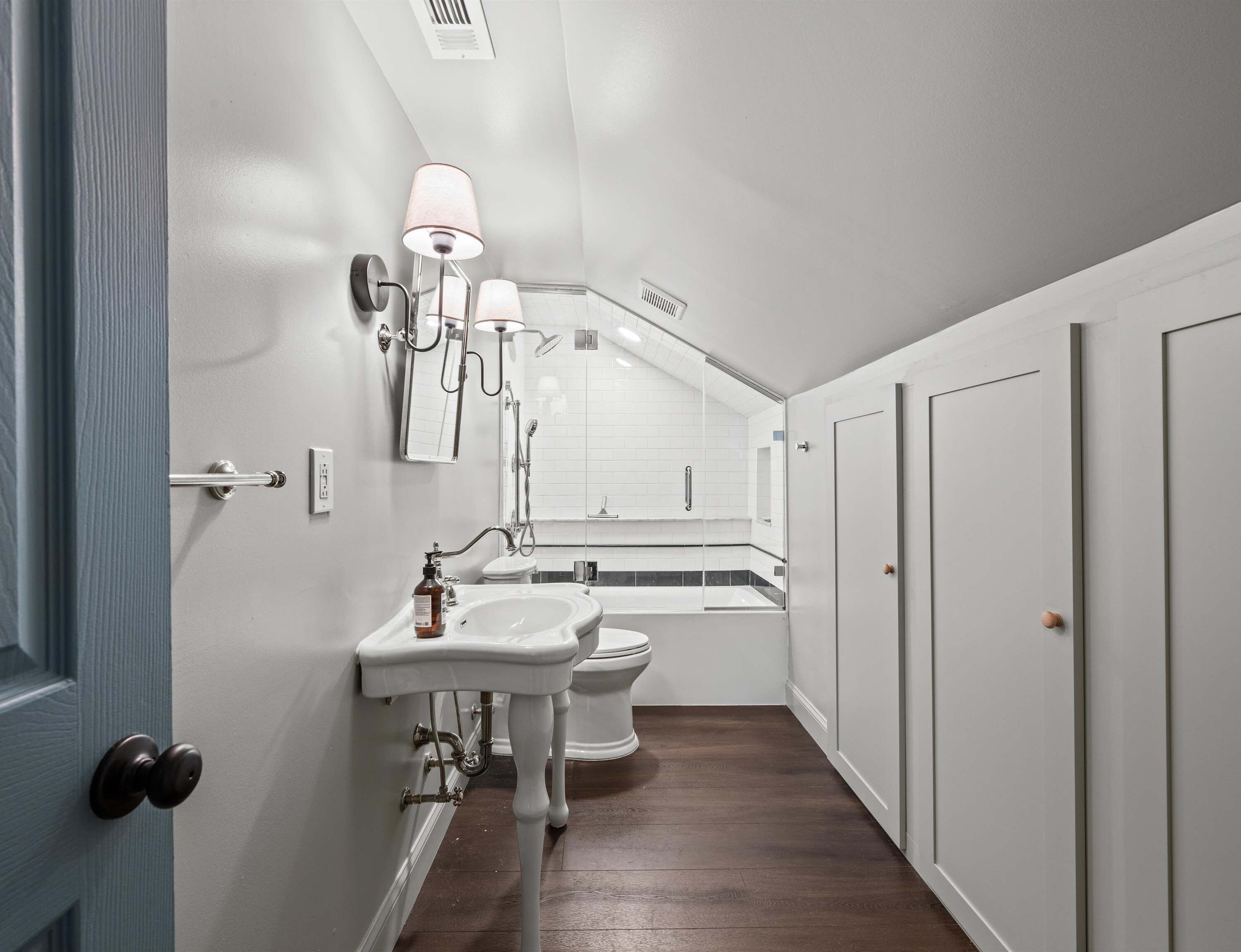 Ein schmales Badezimmer mit Waschbecken, Toilette und Dusche, alles in Weiß.