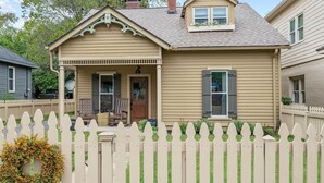 A two-story house with a porch, a small attached garage, and a picket fence. - The Franklin House, Home for 6 (Franklin)