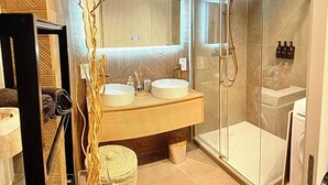 Ein modernes Badezimmer mit zwei Waschbecken, einer Duschkabine aus Glas und einem großen Spiegel.