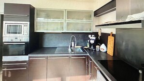 Eine moderne Küche mit Edelstahlgeräten, inklusive Backofen, Mikrowelle, Spüle und Kaffeemaschine.