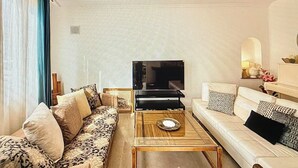 Ein Wohnzimmer mit Sofa, Couchtisch, Fernseher und Deckenventilator.