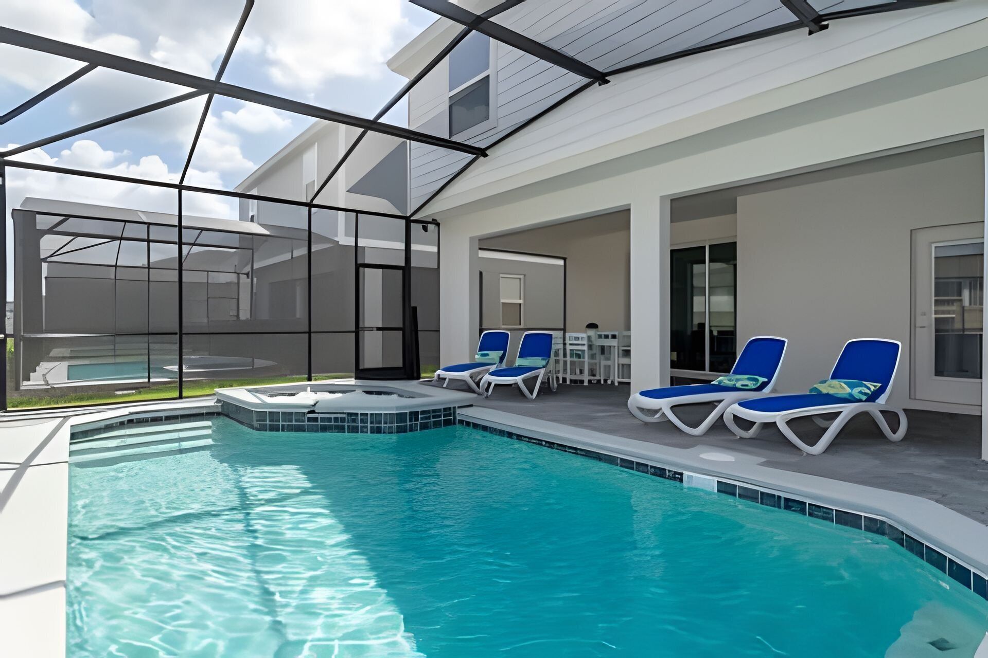 A swimming pool with lounge chairs and a covered patio area.