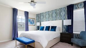 Ein modernes Schlafzimmer mit einem großen Bett, einem Nachttisch, einer Bank und einem Sessel.