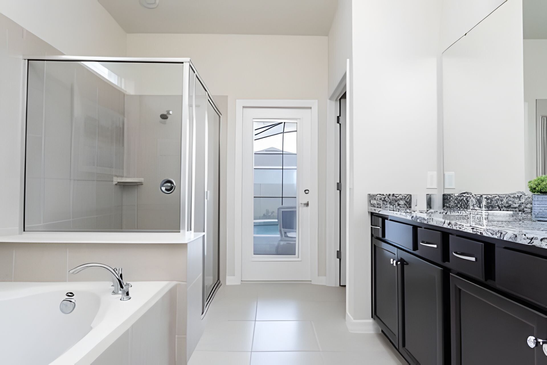 Een moderne badkamer met een douchecabine van glas, een wit ligbad en een grote spiegel boven de wastafel.