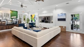Amplia sala de estar con un sofá seccional blanco grande, una mesa de comedor y una zona de cocina con barra.