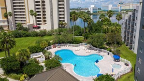 Ein Hotel mit einem großen Pool, umgeben von Palmen und Blick auf ein Gewässer.