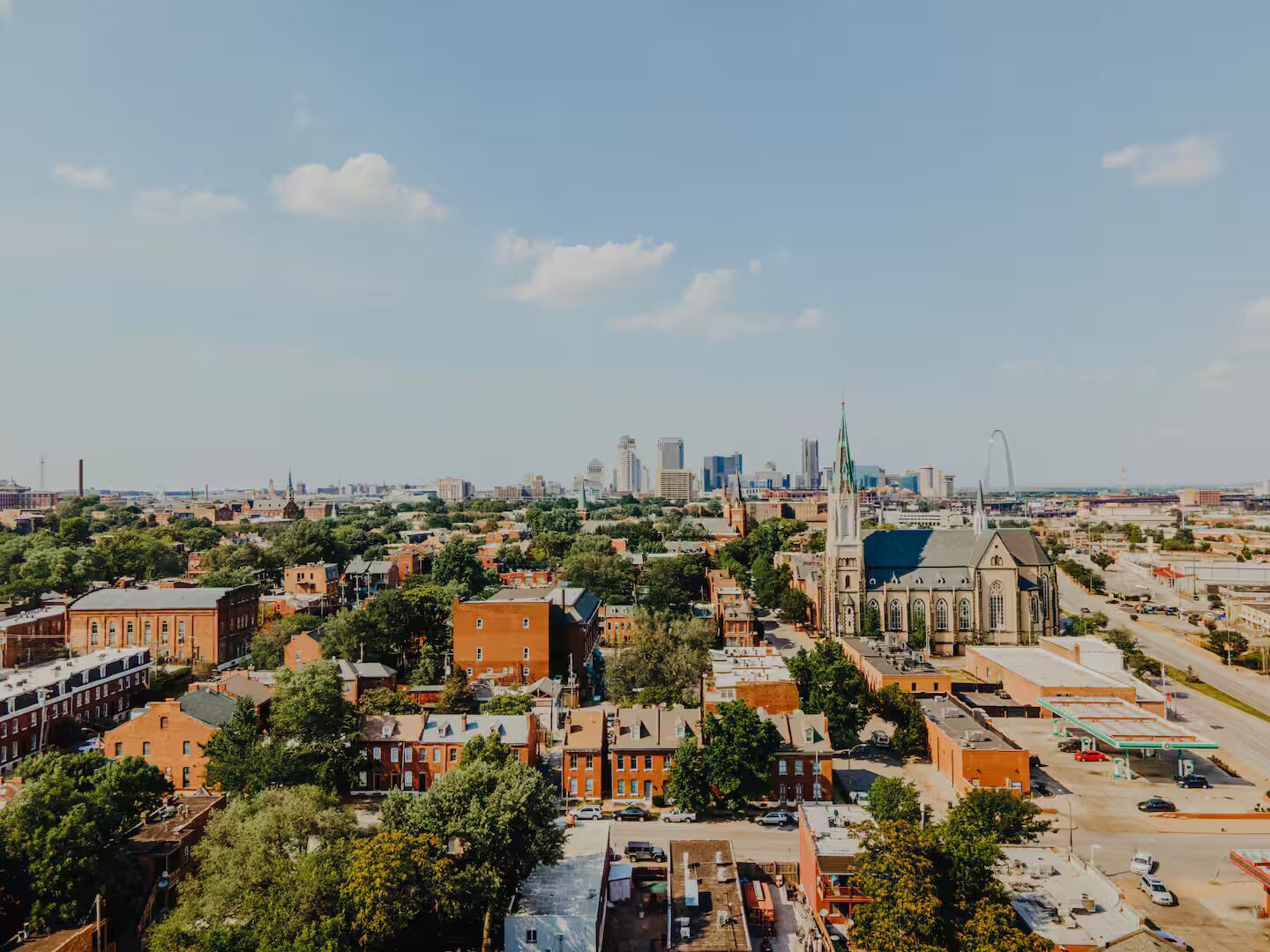 A cityscape with a prominent church, a mix of residential and commercial buildings, and a distant skyline with high-rise buildings.