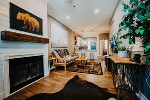 Un salon moderne avec une cheminée, un plancher en bois et un grand tapis.