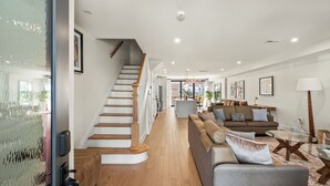 Ein modernes Interieur mit einer Treppe, einem Wohnbereich mit Sofa und Couchtisch sowie einem Essbereich.