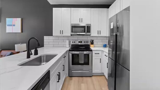 Una cocina moderna con armarios blancos, electrodomésticos de acero inoxidable y encimera de mármol.