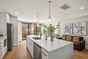 Una cocina moderna con una isla central, electrodomésticos de acero inoxidable e iluminación colgante.
