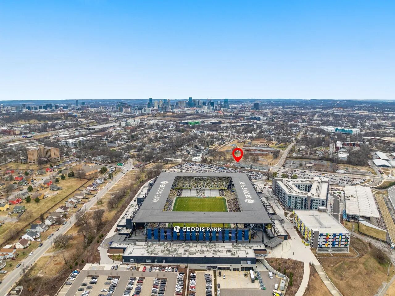 An aerial view of Geodis Park stadium with a parking lot and surrounding buildings.