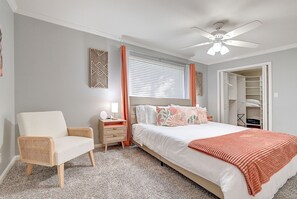 Ein Schlafzimmer mit Bett, Sessel, Nachttisch, Deckenventilator und Kleiderschrank.
