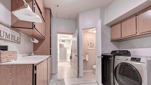 Een moderne keuken met houten kastjes, een ingebouwde wasmachine en een keukeneiland met spoelbak en opbergruimte.