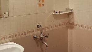 A bathroom with a sink, mirror, shower, and patterned floor tiles. - The Thekkady Haritham Residency  (Kumily)