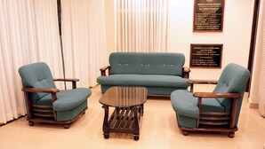 A room with a blue sofa, two matching armchairs, and a small round table. There are two plaques on the wall. - The Thekkady Haritham Residency  (Kumily)