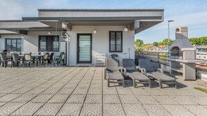 Eine Dachterrasse mit Außenmöbeln, einer Tür und einem Steinbau.