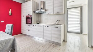 Eine moderne Küche mit hellen Holzschränken, einem eingebauten Backofen und einer Spüle aus Edelstahl.