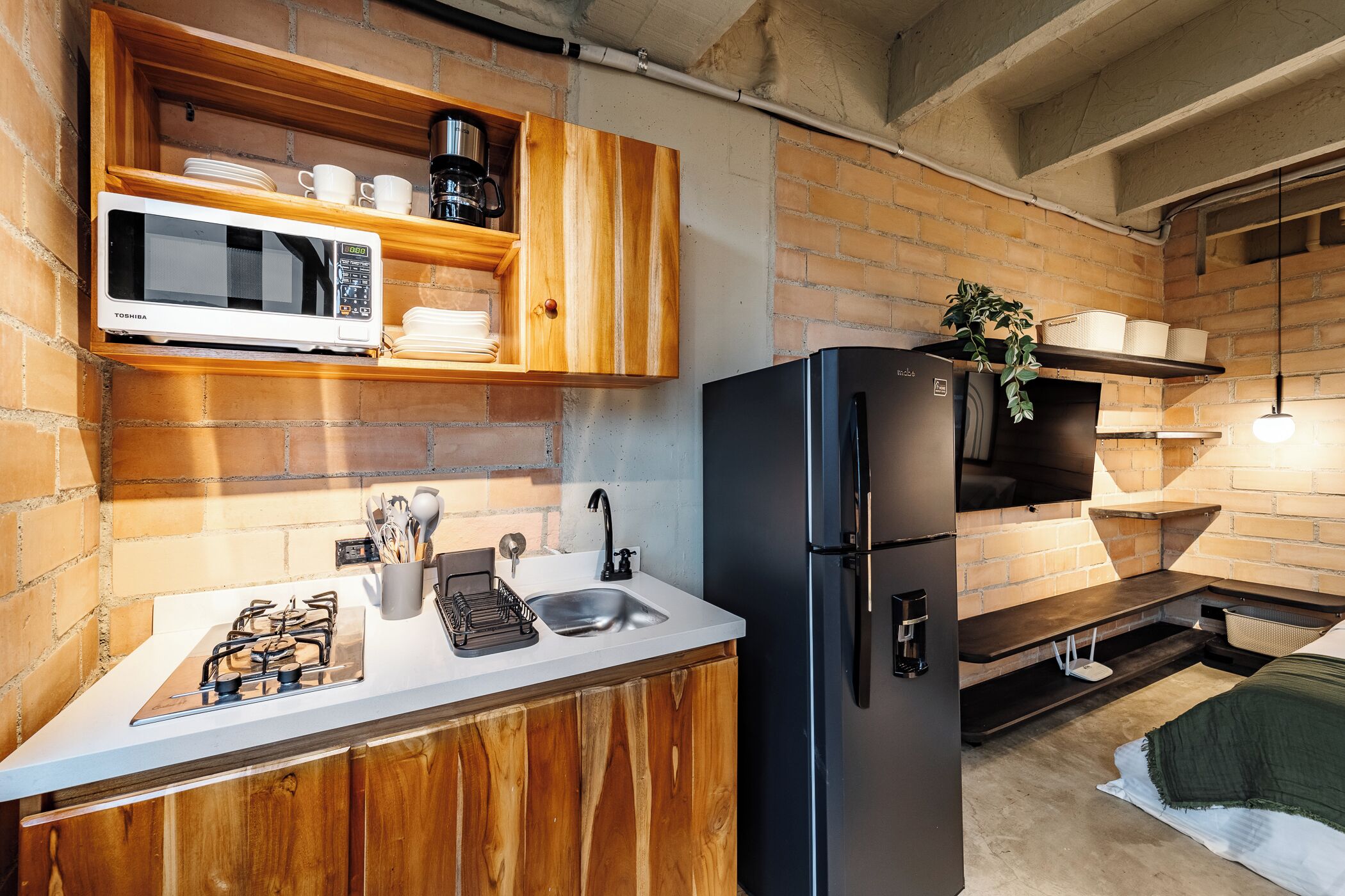 Una cocina compacta equipada con microondas, estufa, fregadero y refrigerador.