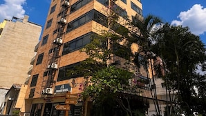 Ein mehrstöckiges Gebäude mit moderner Architektur, ein markanter Eingang mit Beschilderung und umliegender Bepflanzung.