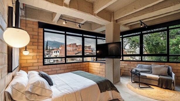 Ein modernes Schlafzimmer mit einem großen Bett, einer Couch und einem an der Wand befestigten Fernseher.