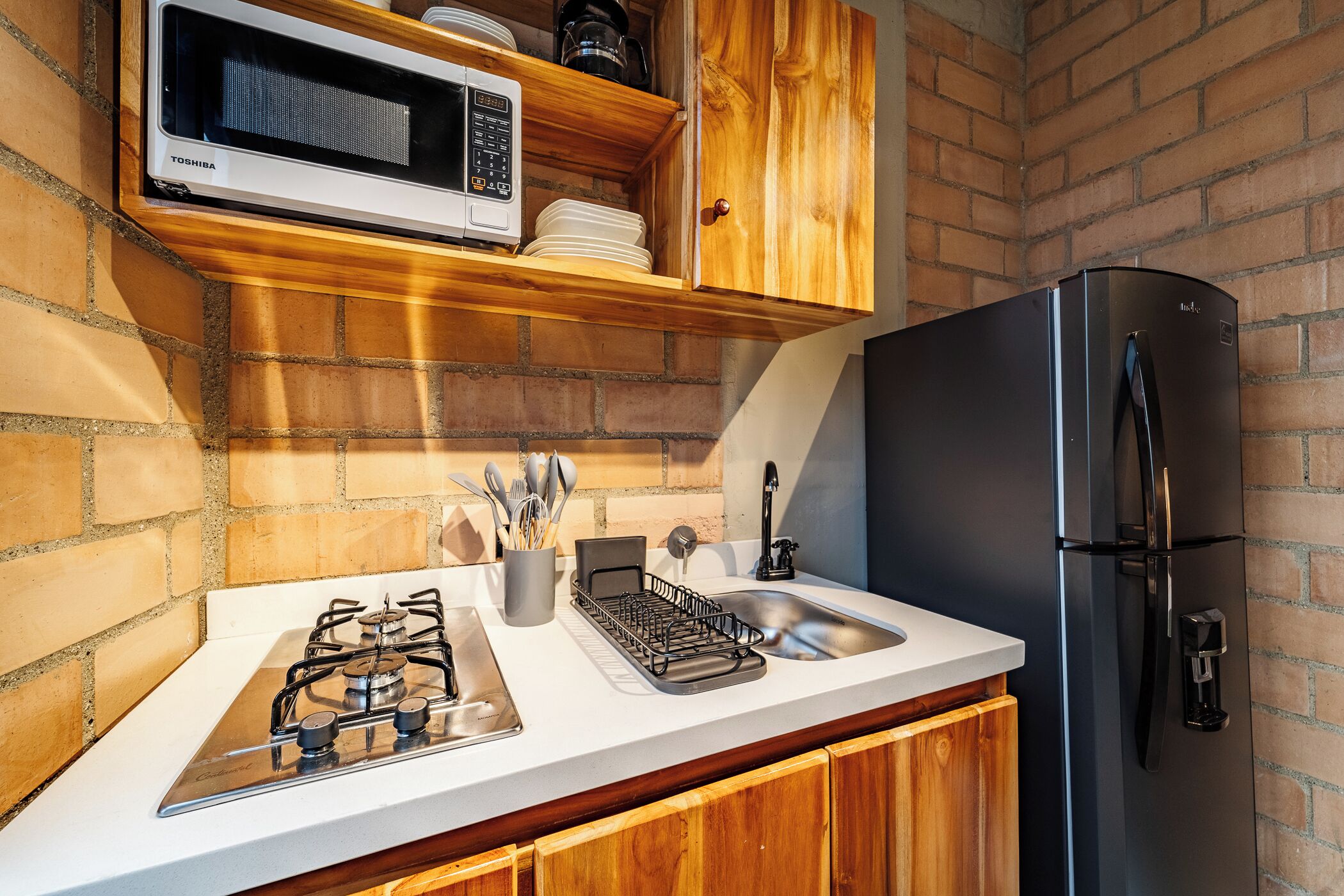 A kitchen with a gas stove, microwave, sink, and refrigerator.