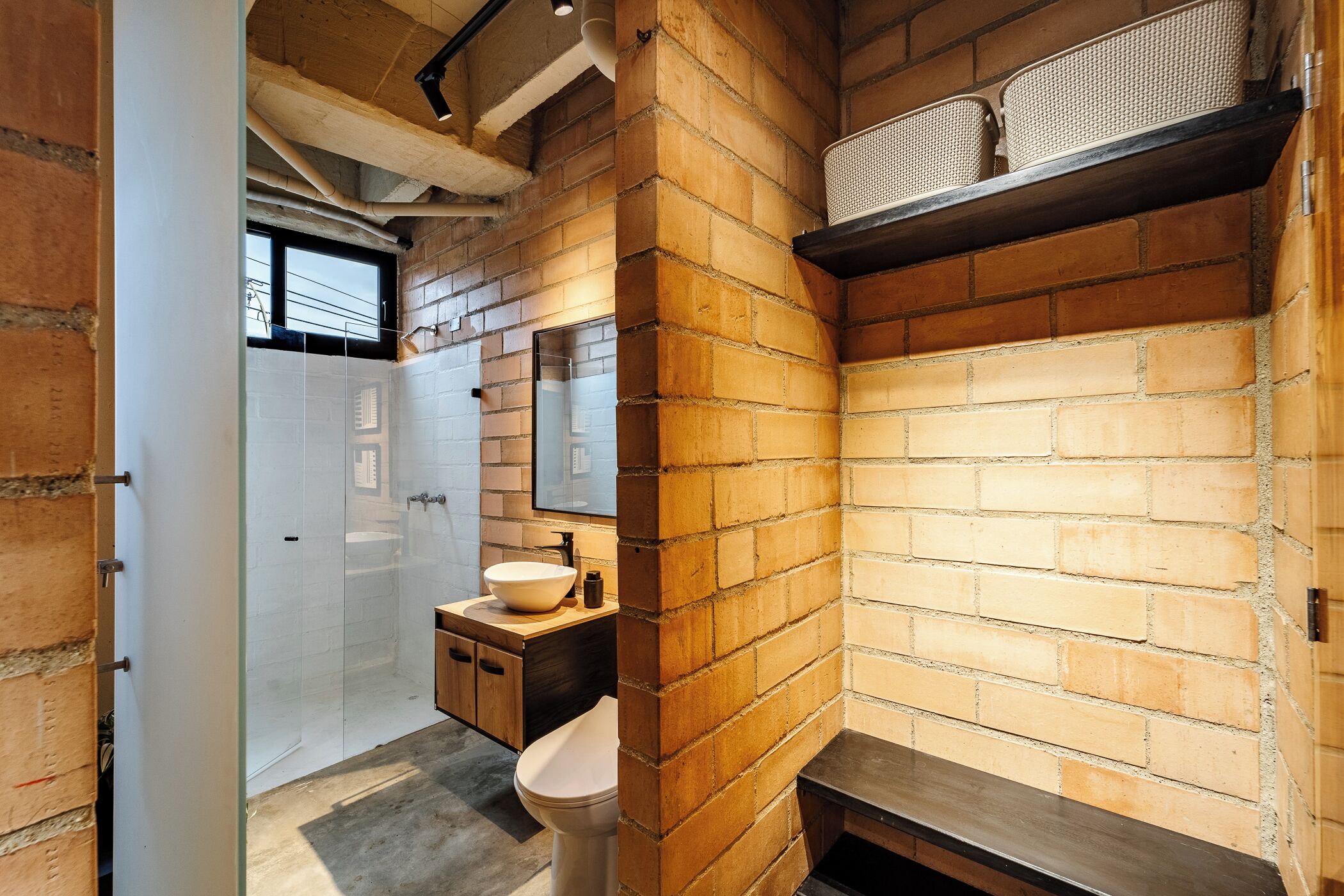 A bathroom with a white toilet, a sink with a mirror, and a shower area.