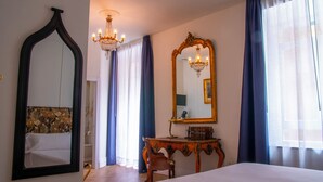 A hotel room with a large bed, a wooden dresser, a mirror, and a chandelier. - Pries Homes - La casa azul (Málaga)