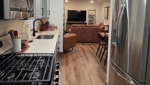 Una cucina moderna con elettrodomestici in acciaio inossidabile, un'isola centrale e un'area pranzo con divano e tavolo.