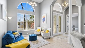 A spacious living room with a blue sofa, white armchairs, and a yellow throw blanket. - Waterfront Haven of Sunshine (Cape Coral)