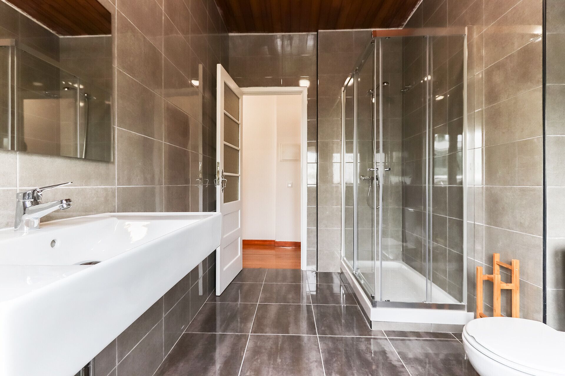 Ein modernes Badezimmer mit einer großen weißen Badewanne, einer gläsernen Duschkabine und Holzboden.