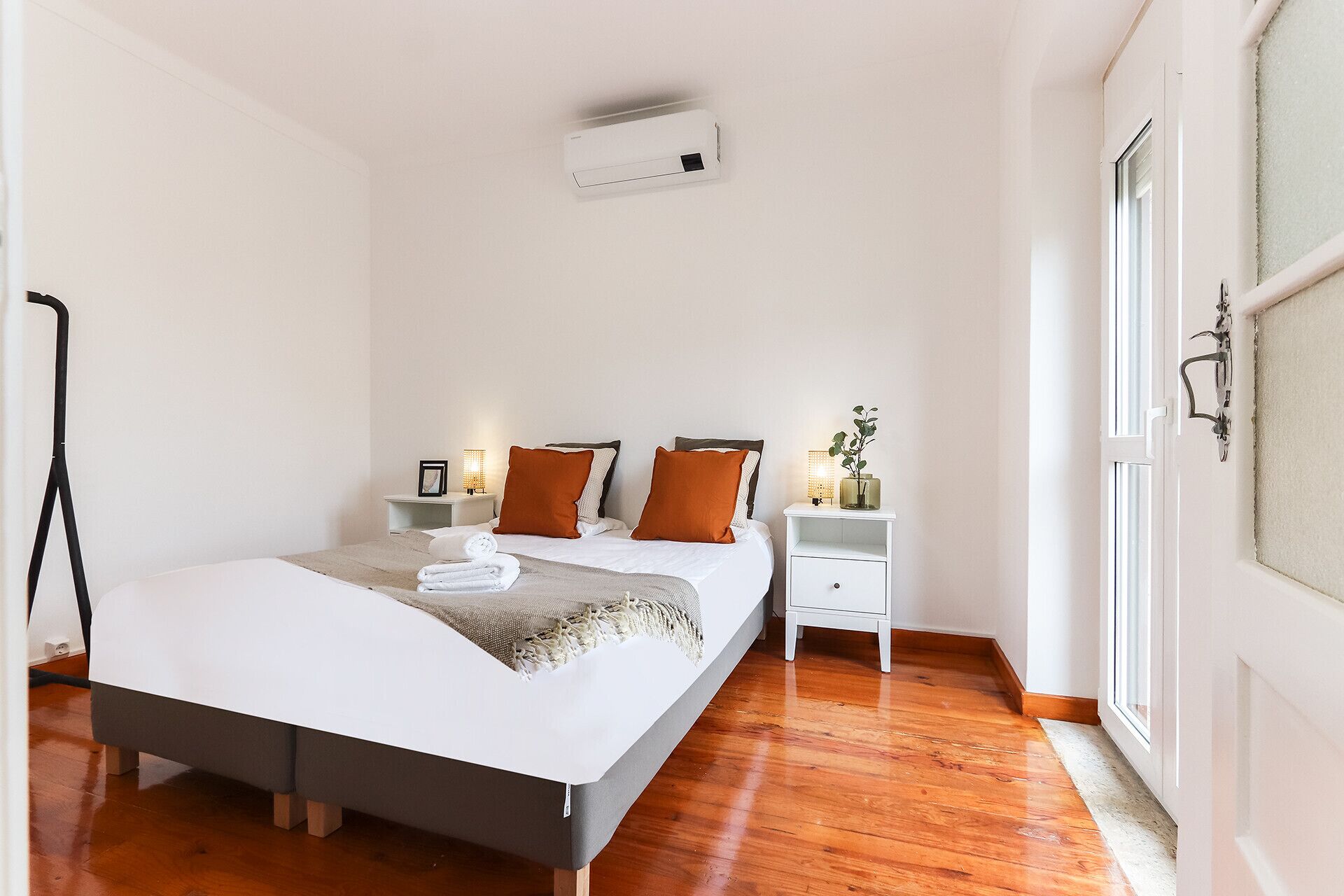 A bedroom with a bed, bedside tables, a lamp, and a window.