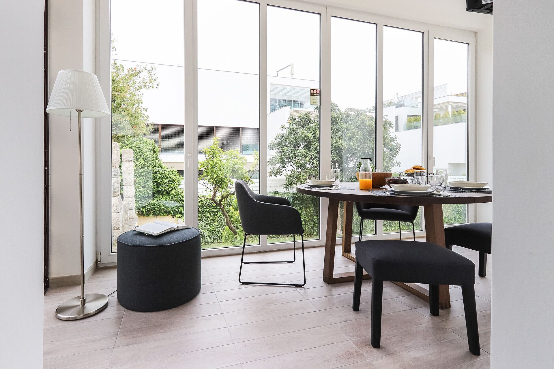 A dining area with a table set for four, large windows, and a floor lamp.