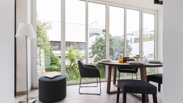 Un coin repas avec une table dressée pour quatre personnes, de grandes fenêtres et un lampadaire.