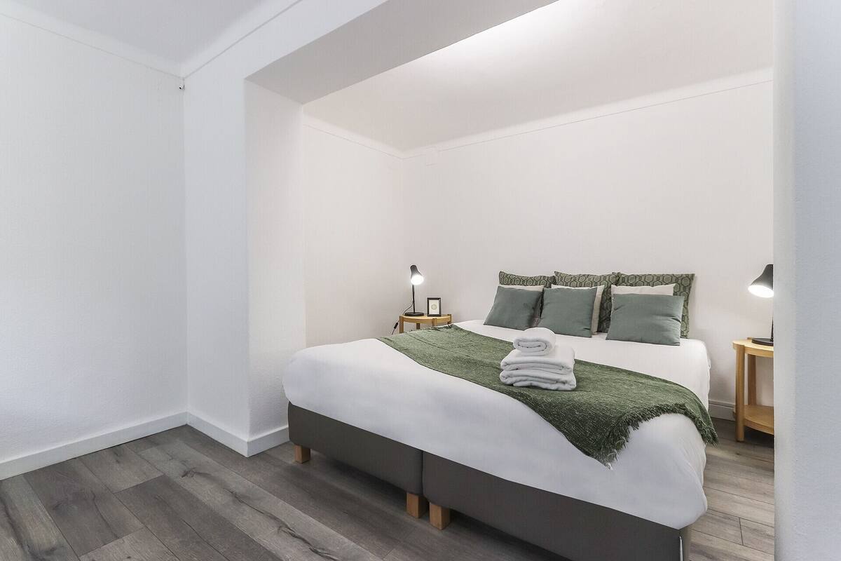 Una camera da letto moderna con un letto grande, due comodini e una coperta verde.
