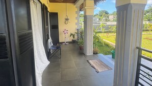 A covered outdoor area with a tiled floor, a ceiling with a geometric pattern, and a view of a green landscape. - CHARMING VILLA WITH GARDEN AND HOUSE STAFF IN NOSY BÉ, CLOSE TO THE BEACHES (nosy be)