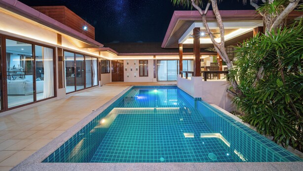 Una casa moderna con piscina, ampie finestre e vista sul cielo notturno.